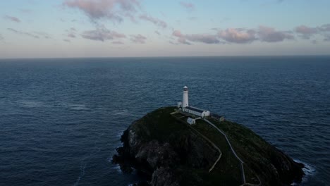 Luftaufnahme-Des-Leuchtturms-South-Stack,-Der-Sich-Dem-Nautischen-Wahrzeichen-Der-Insel-Nähert,-Und-Meereslandschaft-Am-Frühen-Morgen