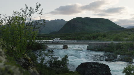 Ein-Wohnmobil-überquert-Eine-Brücke-über-Einen-Wildwasserfluss,-Umgeben-Von-Einer-Wunderschönen-Landschaft-In-Den-Norwegischen-Bergen-Bei-Jotunheimen