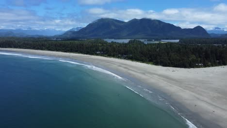 Coastal-view-of-Tofino's-beach-on-Vancouver-Island,-surrounded-by-mountains-and-forest