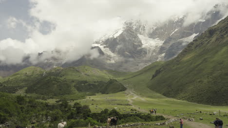 Tourists-ascend-mountain-with-Humantay-Salkantay-Mountain-in-background