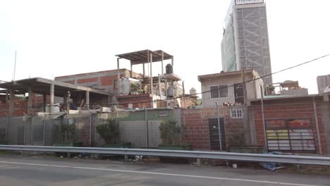 Driving-POV-at-Buenos-Aires-Retiro-slum-houses,-poor-latin-Villa-31-dangerous-neighborhood-with-contrasted-Argentine-high-buildings