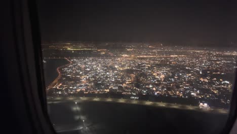 Aerial-shot-of-dubai-city-during-night-time-through-a-plane-window