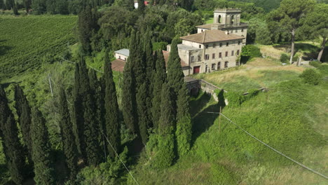 Abandoned-Italian-villa-surrounded-by-tall-cypress-trees-and-lush-green-landscape