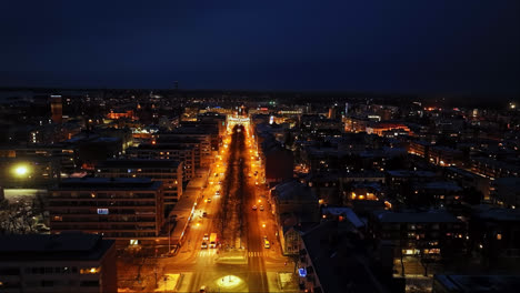 Drone-flying-over-the-Kauppapuistikko-street,-winter-night-in-Vaasa,-Finland