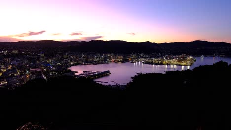 La-Capital,-Wellington,-Por-La-Noche-Con-Las-Luces-De-La-Ciudad-Y-El-Agua-Del-Puerto-Durante-El-Cielo-Púrpura-Del-Atardecer-En-Nueva-Zelanda,-Aotearoa