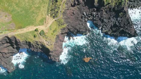 Rocky-coastline-at-miraduro-das-pedras-negras-with-waves-crashing-on-the-shore,-aerial-view