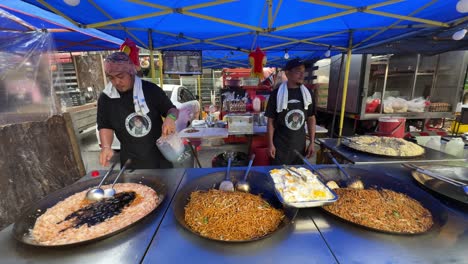 Street-food-vendors-stir-fried-ingredients-in-KSL-Night-Market,-Johor-Bahru,-Malaysia