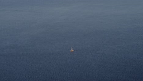 A-lone-sailboat-drifts-in-the-vast-blue-sea-near-Lofoten,-Norway,-creating-a-serene-and-tranquil-scene