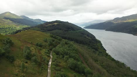 Wunderschöne-Grüne-Talluft-über-Dem-Berg,-Feldweg-Und-See-Im-Schottischen-Hochland,-Schottland,-Großbritannien