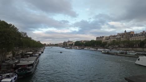 Sightseeing-tourist-boats-move-along-the-river-Seine-with-a-view-of-downtown-Paris-and-its-buildings-in-the-background