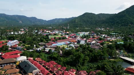 Aerial-of-Lamai-resort-beach-town-village-surrounded-by-mountains-rainforest-in-Koh-Samui-island-in-the-gulf-of-Thailand-drone-footage