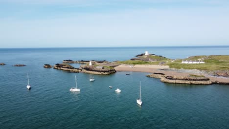 Luftaufnahme-Von-Sightseeing-Yachten,-Festgemacht-Am-Atemberaubenden,-Friedlichen-Strand-Der-Walisischen-Insel-Ynys-Llanddwyn