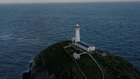 Luftaufnahme-Des-Leuchtturms-South-Stack-Mit-Blick-Auf-Das-Zerklüftete-Wahrzeichen-Der-Insel-Während-Des-Sonnenaufgangs-Zur-Goldenen-Stunde