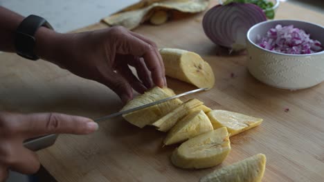 Cortar-Plátano-Amarillo-En-Trozos-Pequeños-E-Ingredientes-Especiales-Para-Cocinar-Una-Comida-Dos-Latas-De-Frijoles-Arroz-Plátano-Aguacate-Cebolla-Roja-Y-Cilantro