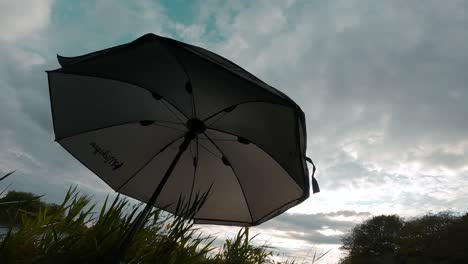 Bajo-La-Sombra-De-Una-Sombrilla-Al-Aire-Libre,-Cielo-Cubierto-De-Nubes-Grises-De-Lluvia,-Viento-Ligero