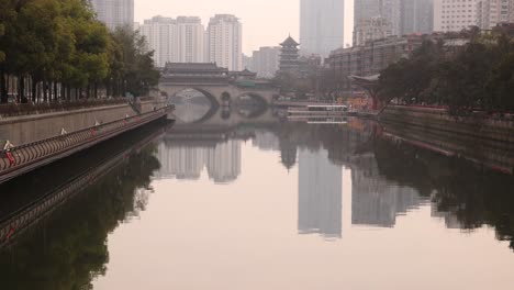 Chengdu-capital-city-of-the-Chinese-province-of-Sichuan,-Anshun-Bridge-over-the-Jin-river-with-modern-skyline-skyscraper-building-in-background-haze-foggy-day