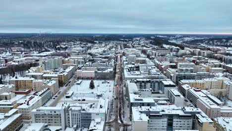 Aerial-view-backwards-over-streets-in-downtown-Lahti,-winter-evening-in-Finland