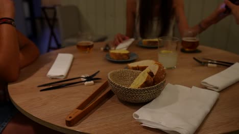 Brot-Und-Getränke-Auf-Dem-Tisch-Mit-Leuten,-Die-In-Einem-Gemütlichen-Restaurant-Speisen