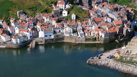 Aerial-drone-view-of-Staithes-Harbour-on-the-North-Yorkshire-coast-with-river,houses,-boats-on-a-sunny-morning-in-August,-summertime