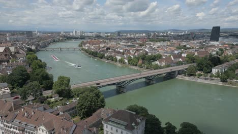 4K-Drone-Video-of-Tugboat-Pulling-Barge-Towards-the-Wettsteinbrücke-Bridge-over-the-Rhine-River-in-Basel,-Switzerland