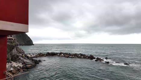 Desde-El-Pueblo-De-Riomaggiore,-Italia,-El-Mar-Más-Allá-De-La-Casa-Roja-Captura-La-Serena-Belleza-Costera.