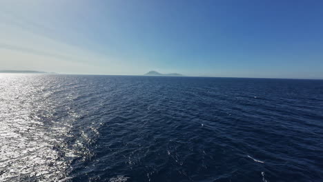 Profile-view-of-seascape-with-ripples-on-blue-sea-and-mountain-at-far-during-daytime-