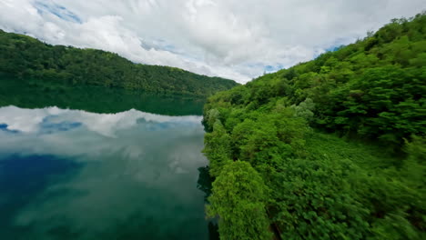 Ruhiger-See,-Umgeben-Von-üppigem-Grünen-Wald,-Mit-Spiegelung-Der-Wolken-Auf-Dem-Wasser