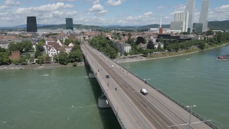 4K-Drone-Video-of-Wettsteinbrücke-Bridge-over-the-Rhine-River-in-Basel,-Switzerland-with-Barges-Approaching