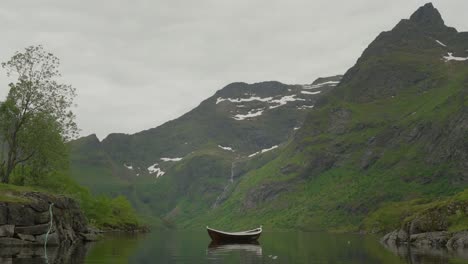 A-tranquil-boat-floating-on-Agavatnet-Lake,-surrounded-by-majestic-mountains-in-Lofoten,-Norway