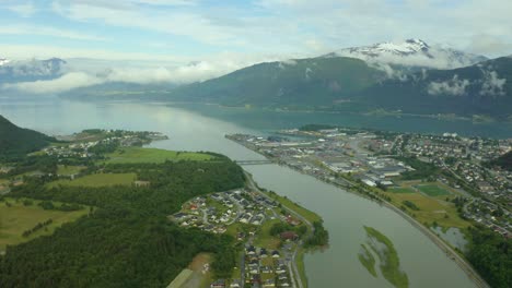 Andalsnes-An-Der-Rauma-Linie-In-Norwegen,-Atemberaubender-Alpensee-Mit-Fluss,-Während-Wolken-Zwischen-Berggipfeln-über-Den-Häusern-Ziehen