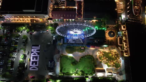 Aerial-view-tilting-away-from-the-illuminated-Asiatique-Sky,-in-Bangkok,-Thailand