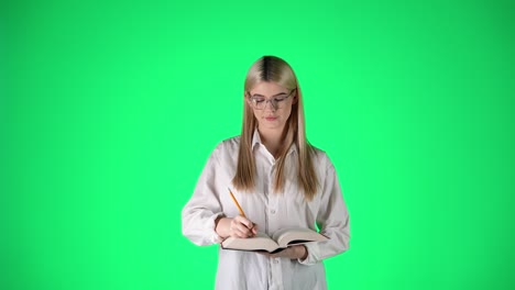 Young-Blonde-Woman-In-White-Shirt-Writing-On-Notebook,-Green-Screen-Background