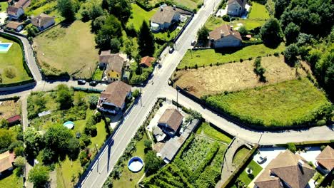 Toma-Aérea-Inmóvil-De-Un-Pueblo-Rural-En-Galicia-Donde-Hay-Un-Automóvil-En-Movimiento-Cruzando-La-Calle-Principal