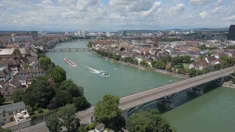 4K-Drone-Video-of-Tugboat-Pulling-Petroleum-Barge-Towards-the-Wettsteinbrücke-Bridge-over-the-Rhine-River-in-Basel,-Switzerland