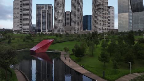 Daytime-view-of-Parque-La-Mexicana-Lake-and-high-rise-buildings,-with-people-running-alongside-the-lake