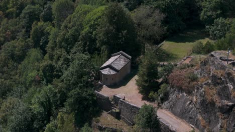 Aerial-footage-of-Abbazia-di-Novalesa-in-Italy,-showcasing-a-serene-medieval-abbey-nestled-amidst-lush-greenery-and-rocky-terrain