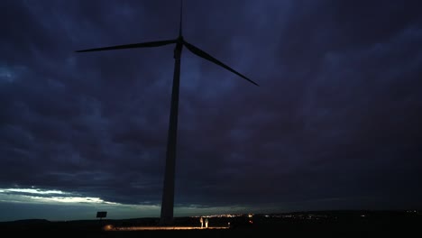 Massive-storm-clouds-over-big-wind-turbine-producing-electricity,-time-lapse