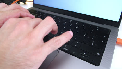 Beautiful-slow-motion-shot-of-young-man's-hands-using-his-macbook-computer-keyboard-for-working-and-searching-information-while-working-from-home