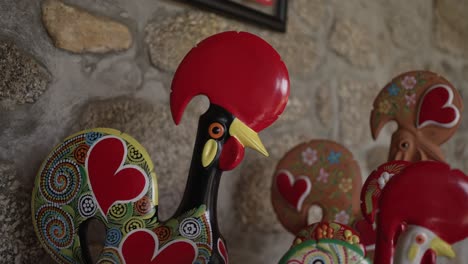 Vibrant,-hand-painted-rooster-figurines-with-heart-motifs,-set-against-a-rustic-stone-wall