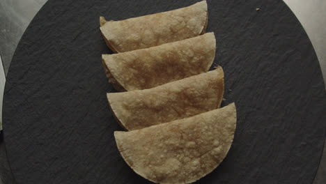 Beautiful-slow-motion-shot-of-the-presentation-of-a-plate-of-4-tacos-or-Mexican-tortillas-dimly-lit-with-white-light-in-an-industrial-kitchen-of-a-Mexican-restaurant