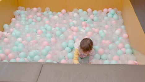 Niña-Rubia-Jugando-En-Un-Estanque-De-Bolas-De-Colores