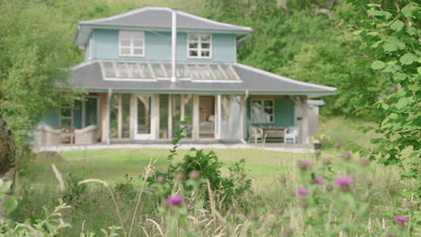 Wooden-double-storey-house-in-lush-woods-on-Scotlands-west-coast,-rack-focus