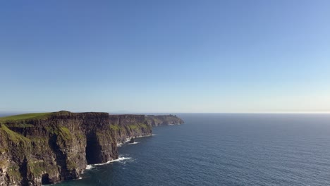 Sunny-blue-sky-day-as-Cliffs-of-Moher-look-over-calm-blue-ocean-water