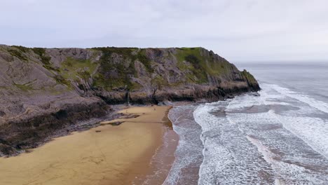 Three-limestone-cliffs,-Gower-coastline-scenery,-incoming-tide,-aerial