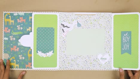 Opens-baby-themed-scrapbook-with-unique-design,-flip-page-with-central-space-for-photograph,-surrounded-by-kiddish-designs