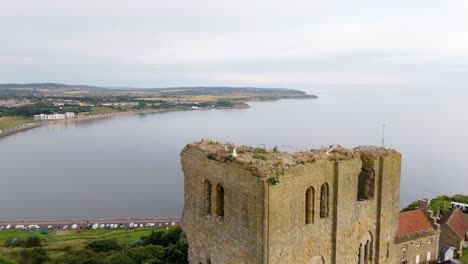 Aerial-drone-view-of-Scarborough-Castle-in-Scarborough,-North-Yorkshire-taken-early-morning-on-an-overcast-day-in-summer