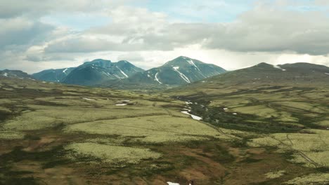 Panorama-Luftaufnahme-Des-Rondane-Nationalparks,-Innlandet-County,-Norwegen-Mit-Schnee-Und-Wasseransammlungen-In-Tiefen-Stellen