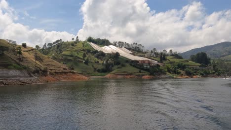 Campos-Agrícolas-Cubiertos-En-La-Costa-Del-Lago-Guatapé,-Vista-Desde-Un-Barco-En-Movimiento,-Colombia