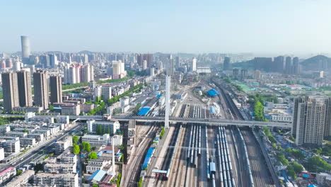 Blick-Auf-Den-Autoverkehr-Auf-Kreuzungen-Von-Straßen-Und-Autobahnen-In-Einer-Modernen-Stadt-Mit-Skyline-Wolkenkratzern-Und-Wahrzeichen-Unter-Blauem-Himmel,-Zeitraffervideo-Einer-Hochgeschwindigkeitszugbrücke