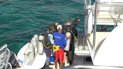 Taucher-Bereiten-Sich-Auf-Einem-Boot-Im-Klaren,-Blauen-Wasser-Auf-Einen-Tauchgang-Vor